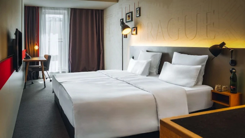 Modernt hotellrum p� Hotel Pulse 8 i Tjeckien med tv� separata s�ngar, skrivbord, platt-TV och stilren inredning i ljusa f�rger.